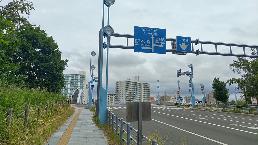 幌平橋駅1番出口から幌平橋方面へ向かう歩道と道路標識。南7条大橋、真駒内、中央線方向の案内が見える