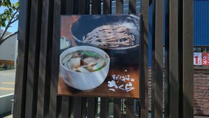 そばとつゆの写真が入った手打ちそばさくらの看板。
