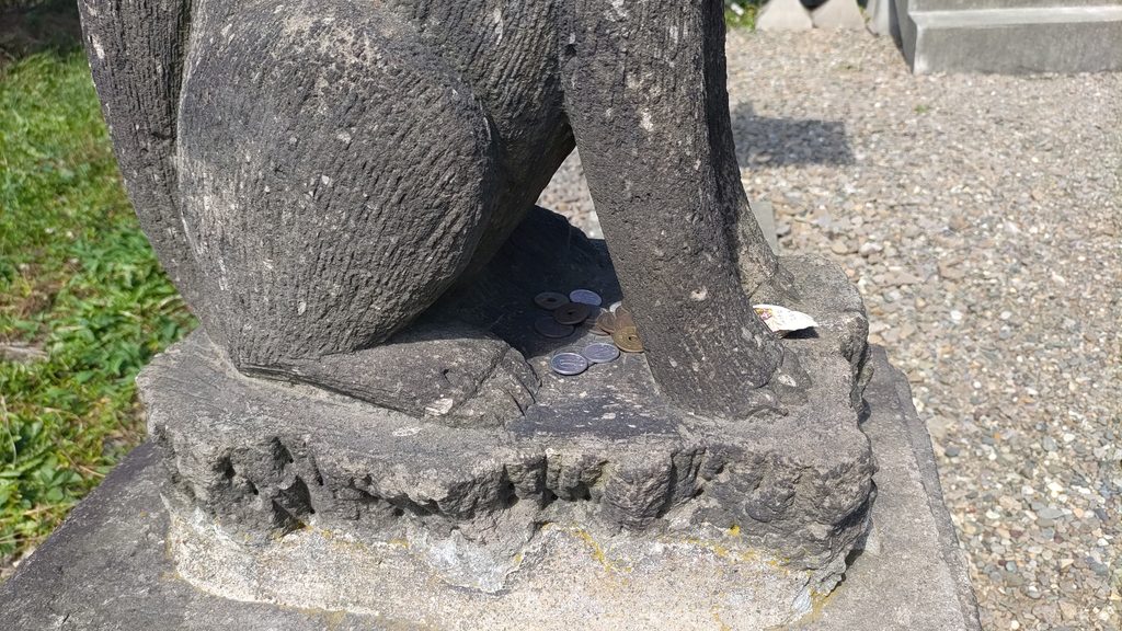 豊畑神社の狛狐の足元に置かれた複数の硬貨
