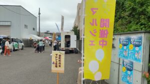 「開催中」の黄色いのぼりと栄町町内会マルシェ会場の案内が立つ会場入口