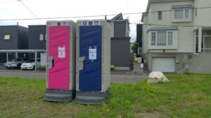 会場西側の草地に設置されたピンク色と青色の仮設トイレ