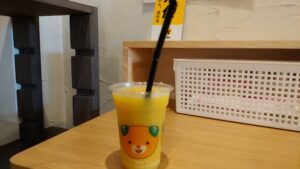 蛇口から注いだみかんジュースが入ったみきゃん柄のカップ