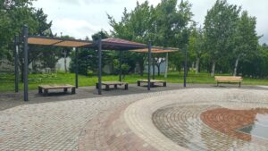丘珠公園の噴水近くにある屋根付きベンチ。水遊びする子どもを保護者が見守りやすい距離感が分かる。2026年7月12日撮影。