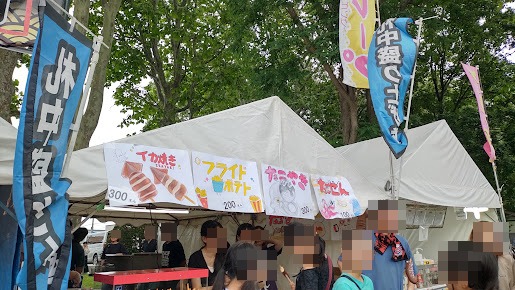 イカ焼き300円、フライドポテト200円、たこ焼き300円、たこせん100円の手書きメニューが並ぶ売店
