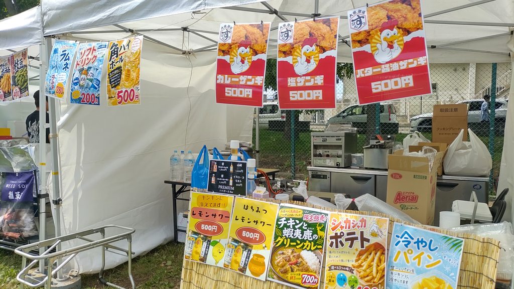 チキン、ポテト、冷やしパイン、ラムネなどのメニューが並ぶ飲食露店