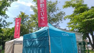 ハッチふれあいフェスティバル会場内の指定喫煙エリア。青いテントと「喫煙エリア」と書かれた赤いのぼりが立っている