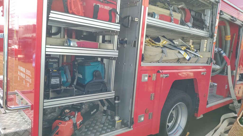 消防車と装備品の展示。実際に消火のホースを出している様子。