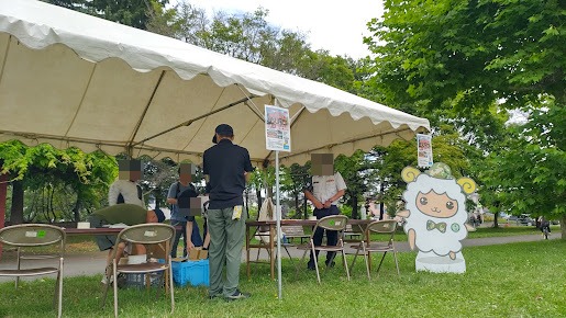 自衛隊コーナーのテントと来場者、羊のキャラクターパネル