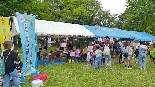 縁日のテント前に並ぶ子どもと保護者