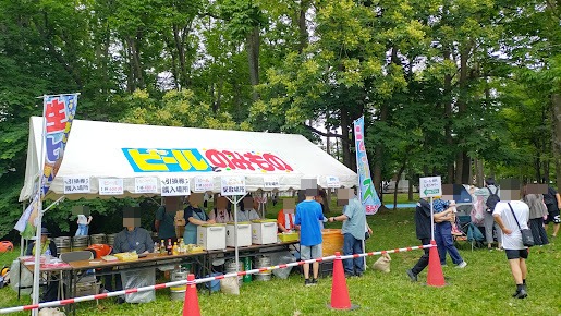 ビールや飲み物を販売するテントと、商品を受け取る来場者
